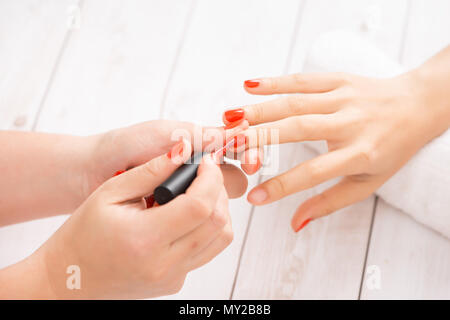 Donna ottenere unghie manicure. Manicurist applicando red Nail Polish per cliente. Foto Stock