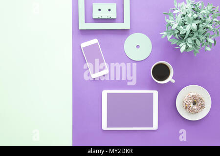 Mockup del freelancer di smartphone e tablet su ultra violet scrivania con tazza di caffè e ciambelle Foto Stock