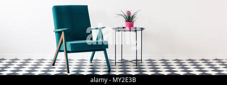 Poltrona verde e metallo fine tabella con pianta fresca in rosa pot in piedi in camera bianca interno con posto per la vostra sedia Foto Stock