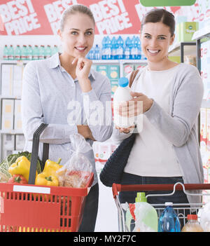 Amici facendo la spesa insieme al supermercato, essi sono sorridente alla fotocamera e posa Foto Stock