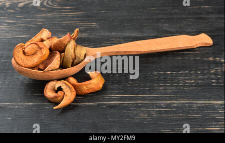 Fette di mela essiccata in un cucchiaio su sfondo di legno Foto Stock