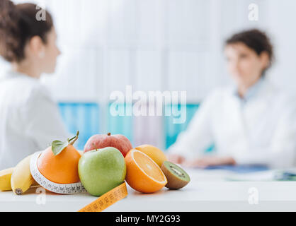 Nutrizionista professionista incontro un paziente in ufficio e sani frutti con nastro di misurazione in primo piano : una sana alimentazione e dieta concetto Foto Stock