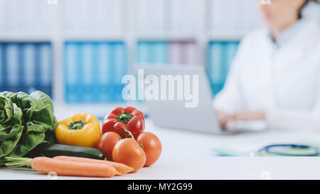 Nutrizionista professionista lavora in ufficio e sano di verdure fresche in primo piano: la dieta e il concetto di salute Foto Stock