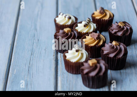 Tortine decorate con cioccolato,caramello e vaniglia ciliegina su uno sfondo di legno Foto Stock