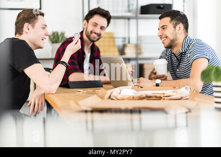 Gruppo di amici sorridente e cercando in corrispondenza di un token in un ufficio Foto Stock