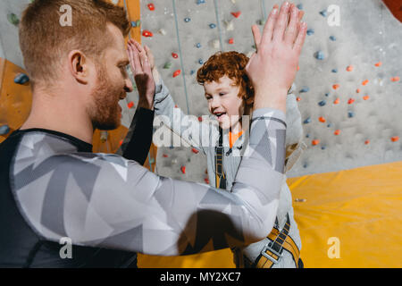 Closeup colpo di Little Boy nel cavo elettrico ad alta fiving suo papà con pareti di arrampicata in bacackground Foto Stock