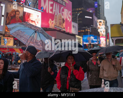 NEW YORK, NY - 16 Maggio 2018: Walkers tenere gli ombrelli la visualizzazione delle insegne al neon di Times Square in un giorno di pioggia Foto Stock