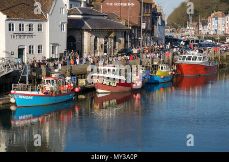 Custom House Quay a Weymouth vista dal ponte della città. La Folla di vacanzieri godere il sole accanto a barche da pesca nel porto. Dorset, Regno Unito Foto Stock