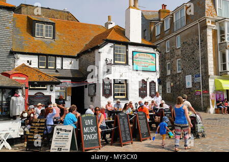 Turisti che si godono il sole al di fuori del Sloop Inn presso il porto, St Ives, Regno Unito Foto Stock