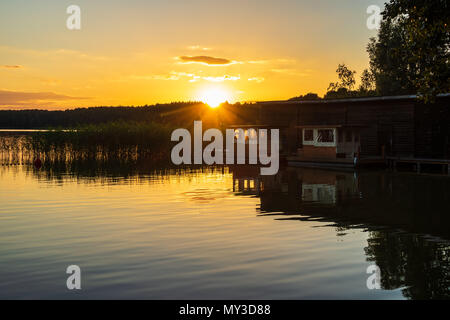 Il panorama su un lago con alberi e boatshouse. Foto Stock