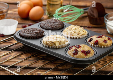Diversi i muffin in bakeware o teglia per muffin su broun sfondo di legno. Muffin di base ricetta. Muffin fatti in casa per la prima colazione o per dessert. Ingredienti Foto Stock
