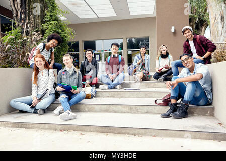 Studenti del college seduti sui gradini fuori dall'edificio, ritratto Foto Stock