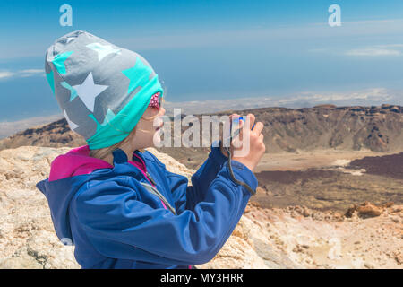 Ragazza con cappuccio fotografie di un paesaggio di montagna nella luce del sole, ritratto, vista laterale, profilo, mezza figura Foto Stock