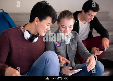 Amici guardando insieme allo smartphone Foto Stock