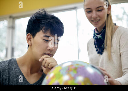 Gli studenti guardando il mondo in classe Foto Stock