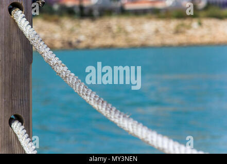 Corrimano di corda fatta di fune contro il mare blu Foto Stock