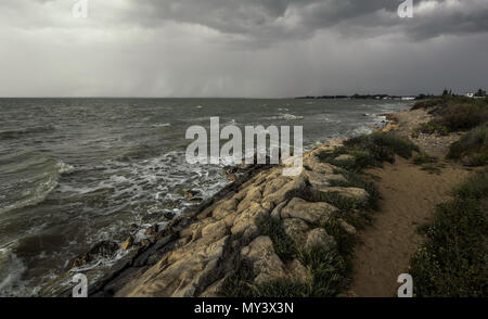 Sentiero sabbioso oltre il frangiflutti sulla spiaggia di Sanlucar de Barrameda in un giorno di tempesta Foto Stock