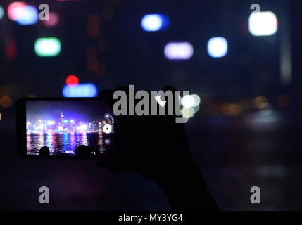 Grattacieli sull isola di Hong Kong di notte come visto attraverso uno smartphone. Foto Stock