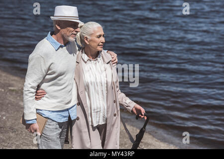 Casual dai capelli grigi giovane camminando sul lungofiume di giorno Foto Stock