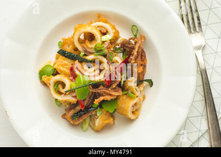 Calamari fritti Calamari, peperoncino e foglie di menta sulla piastra bianca Foto Stock