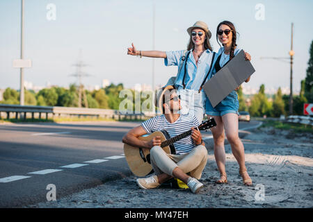 Amici multiculturale con cartone vuoto autostop durante il viaggio insieme Foto Stock