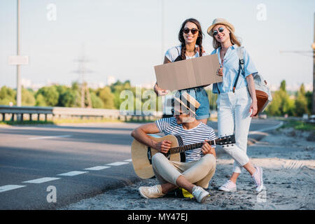 Amici multiculturale con cartone vuoto autostop durante il viaggio insieme Foto Stock