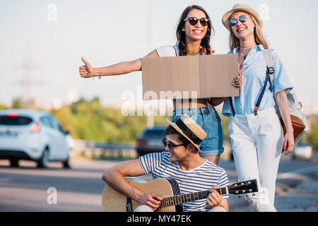 Amici multiculturale con cartone vuoto autostop durante il viaggio insieme Foto Stock