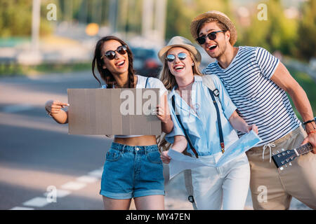 Amici multiculturale con cartone vuoto autostop durante il viaggio insieme Foto Stock