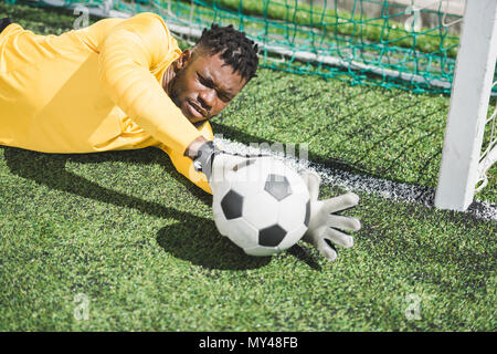 Ritratto di African American portiere cattura la sfera durante la partita di calcio Foto Stock