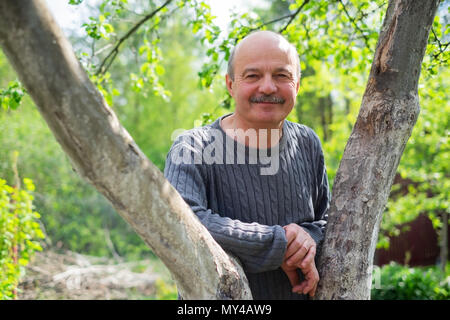 Ritratto di fiducioso giardiniere maschio in piedi nei pressi di alberi da frutto. Foto Stock
