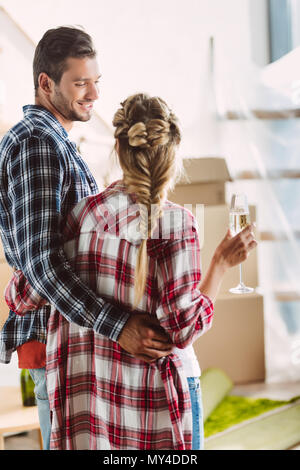 Vista posteriore della coppia giovane bevendo champagne in casa nuova Foto Stock