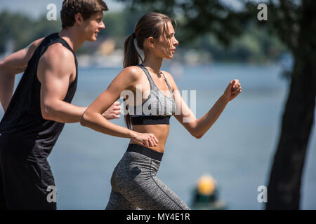 Vista laterale della giovane coppia sportiva insieme per fare jogging nel parco Foto Stock