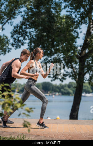 Vista laterale della giovane coppia sportiva insieme per fare jogging nel parco Foto Stock