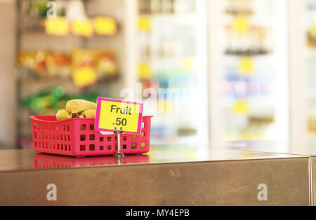 Mensa scolastica negozio di dolciumi caff vendita frutta sani opzioni di cibo per gli studenti. banane in un rosso sul vassoio in acciaio inox panca in primo piano Foto Stock