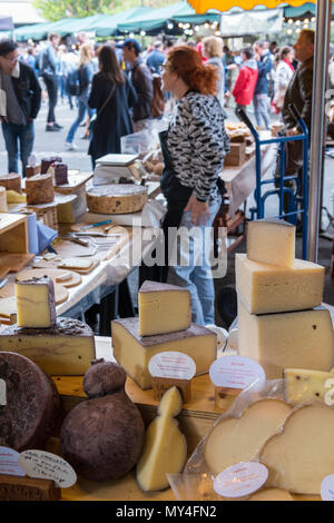 Un formaggio srtall a Londra il mercato biorough la vendita di una grande varietà di salumi e formaggi di specialità. Donna che serve al mercato stallo a Borough Market. Foto Stock