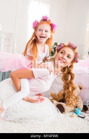 Vista laterale della madre e figlia felice piggybacking insieme a casa Foto Stock