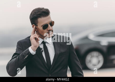 Bello del bodyguard ascolto messaggio con protezione auricolare Foto Stock