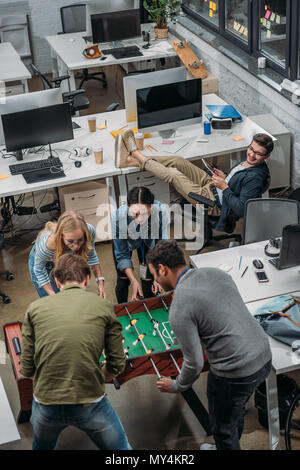 Multiculturale di persone che giocano a calcio balilla presso un ufficio moderno Foto Stock