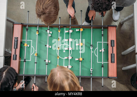 Vista dall'alto ritagliata di multiculturale di persone che giocano a calcio balilla presso un ufficio moderno Foto Stock