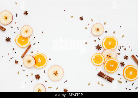 Ingredienti per il vin brulé sul tavolo bianco. Arancione, Apple, cannella, anice, pepe, chiodi di garofano. Vista superiore, piatto laici. Foto Stock