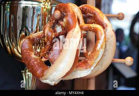 Close-up di freschi di forno Pretzel bavarese appeso su un rack di legno con un metallo salsiccia pot in retro Foto Stock