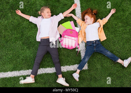 Vista superiore della bella felice studentesse sorridente ogni altra sdraiati sull'erba Foto Stock