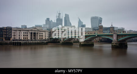 London, England, Regno Unito - 29 Maggio 2018: cieli grigi e inquinamento atmosferico sindone la City of London skyline visto attraverso il Fiume Tamigi da accanto Southwar Foto Stock