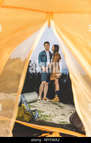 Vista dalla tenda su una giovane coppia in viaggio escursionistico tenendo le mani Foto Stock