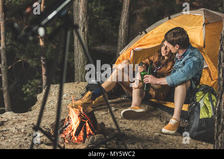 Una giovane coppia in viaggio escursionistico di bere birra in tenda Foto Stock