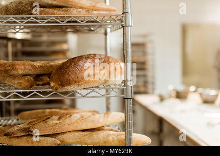 Ripiani con delizioso pane appena sfornato sulla fabbricazione di cottura Foto Stock