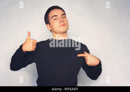 Attraente giovane uomo in t-shirt bianca con punta a destra con il suo dito su sfondo blu. guy in una t-shirt nera punti il dito di una mano a se stesso con il Foto Stock