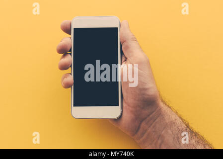 Smartphone con schermo vuoto in mano maschio, dai toni rétro immagine Foto Stock
