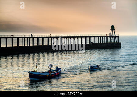 I pescatori in barca a vela nel porto di Whitby di sera dopo la raccolta nelle loro reti a Sandsend sulla North Yorkshire costa. Foto Stock