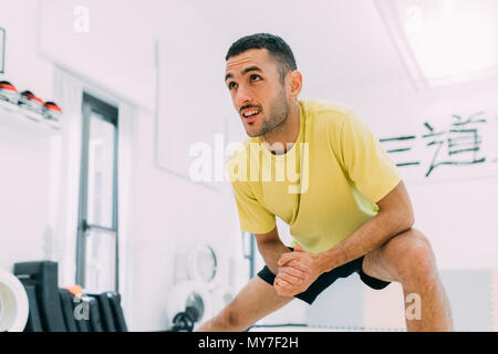 Uomo in palestra facendo esercizi di stretching Foto Stock